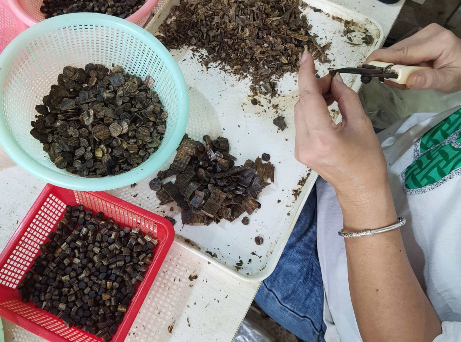 Skilled artisan manually slicing and preparing high-grade Kynam agarwood at KYARASEN workshop.